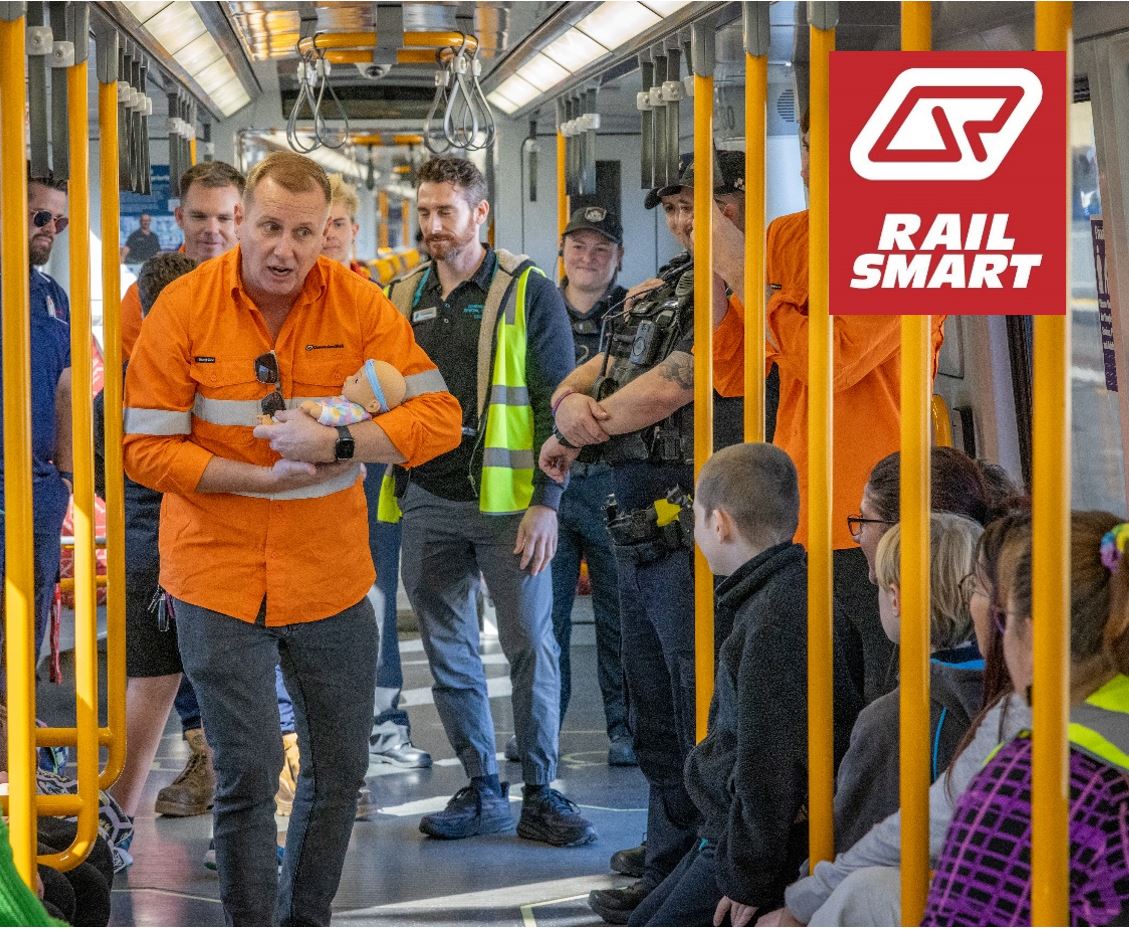 A Community Education Coordinator demonstarting train ettiquette to a group of students on  train
